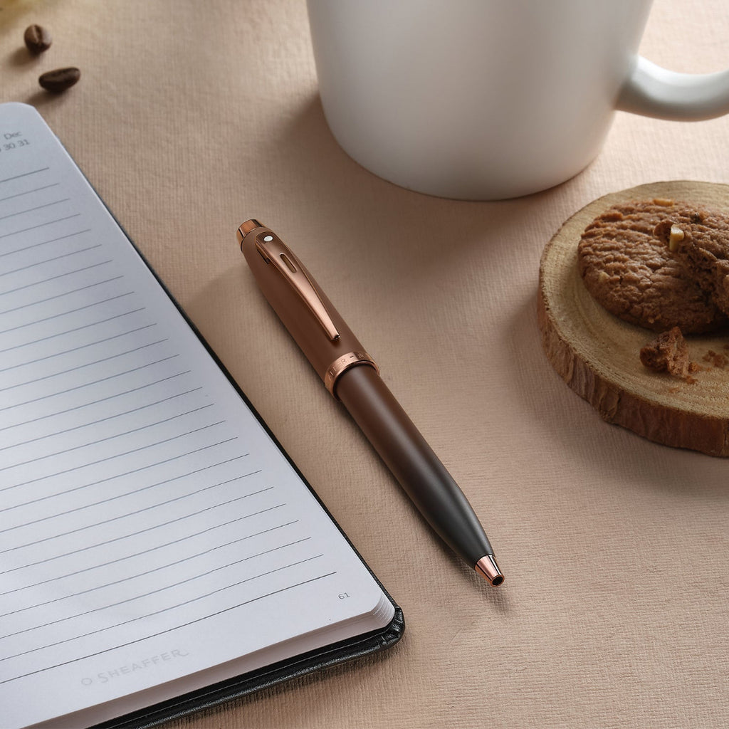 Sheaffer 100 9374 Coffee Edition Matte Brown Ballpoint Pen with Regal Brown PVD Trims on desk with coffee and notebook