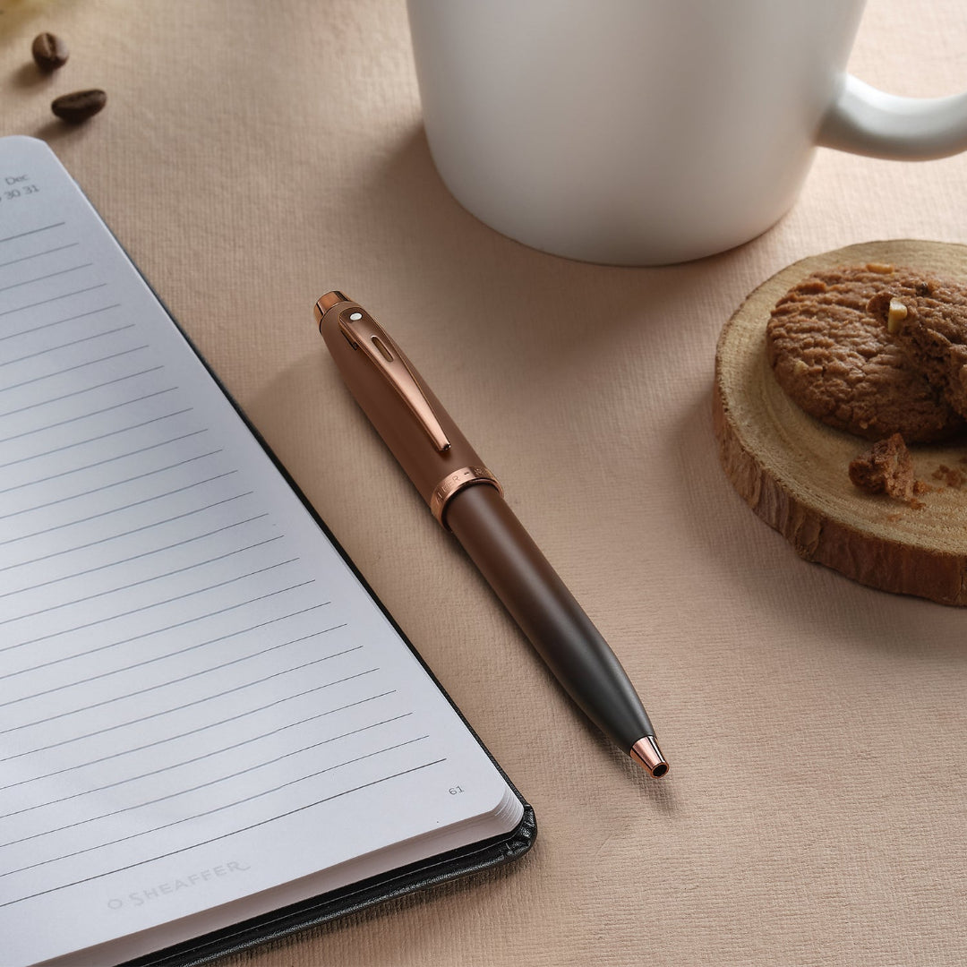 Sheaffer 100 9374 Coffee Edition Matte Brown Ballpoint Pen with Regal Brown PVD Trims on desk with coffee and notebook