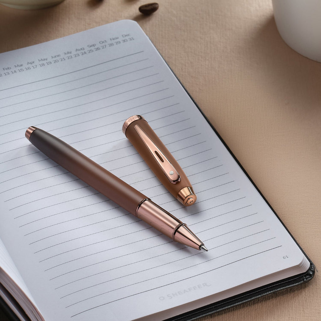 Sheaffer 100 9374 Coffee Edition Matte Brown Rollerball Pen with Regal Brown PVD Trims on top of a planner