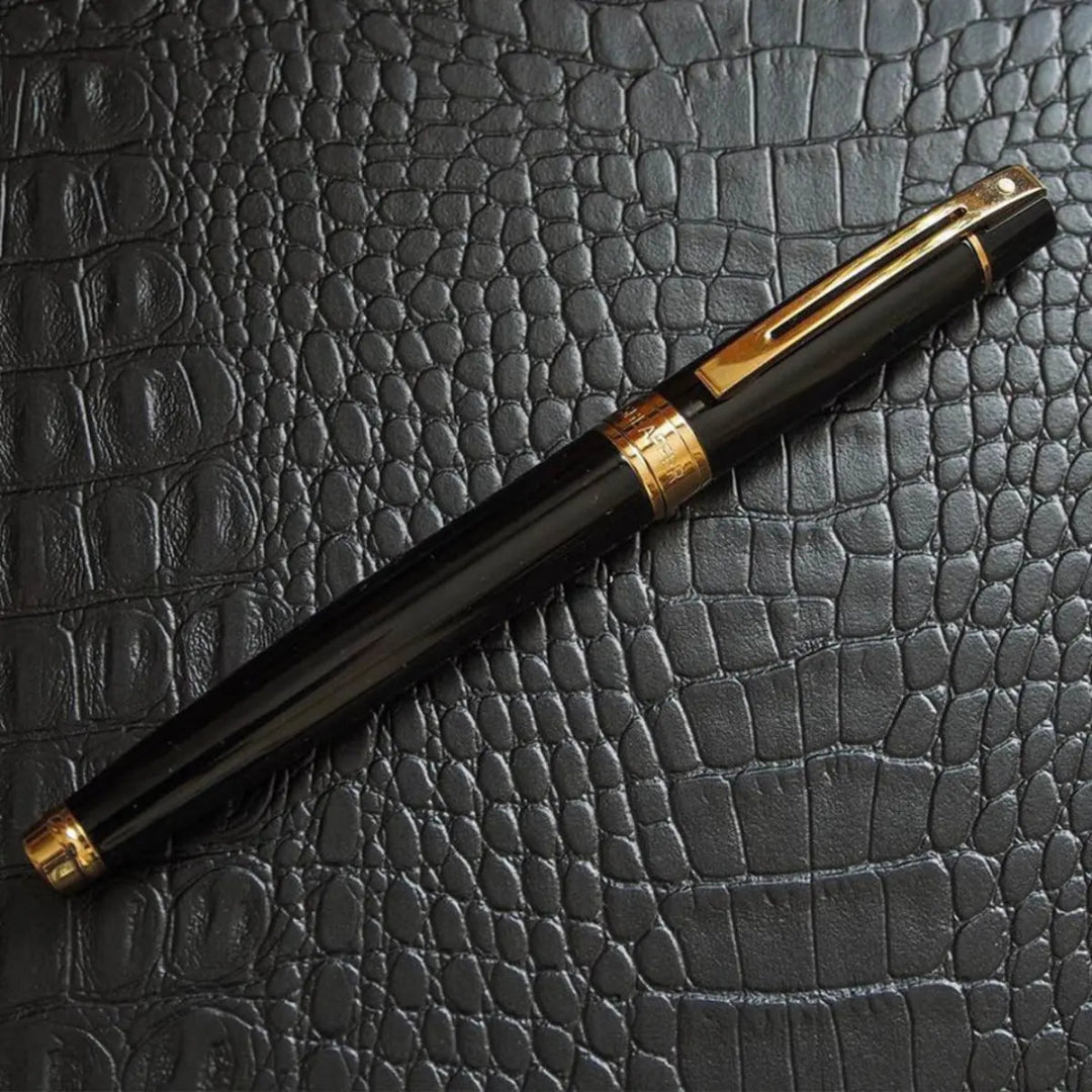 Sheaffer 300 Glossy Black Rollerball Pen with Gold Trims on textured leather surface