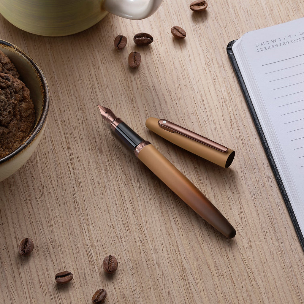 Sheaffer VFM 9428 Coffee Edition Matt Brown Fountain Pen with Regal Brown PVD Trims beside a planner, coffee and cookies